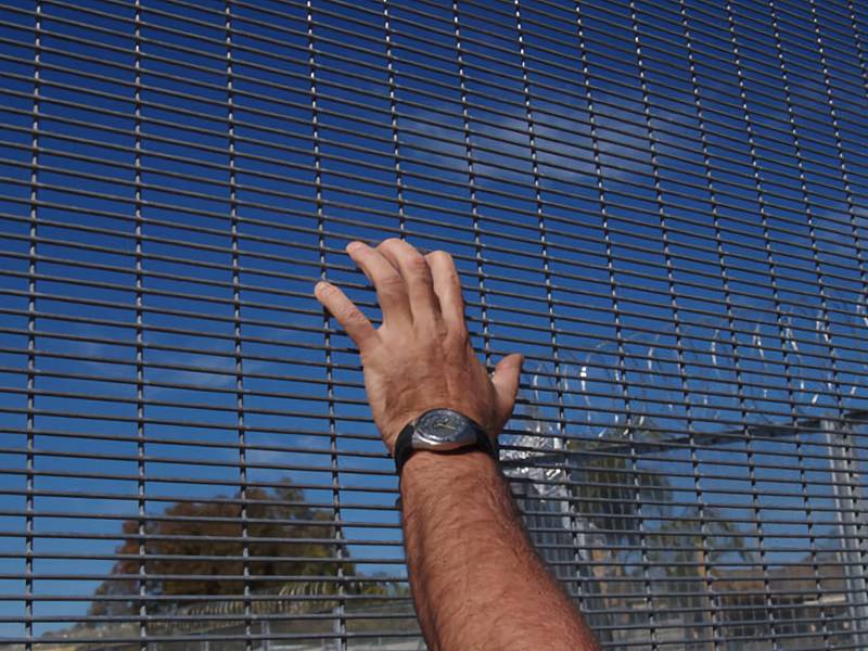 A galvanized welded wire security fence of high height and small mesh size is finger-proof and accompanied by razor wire.